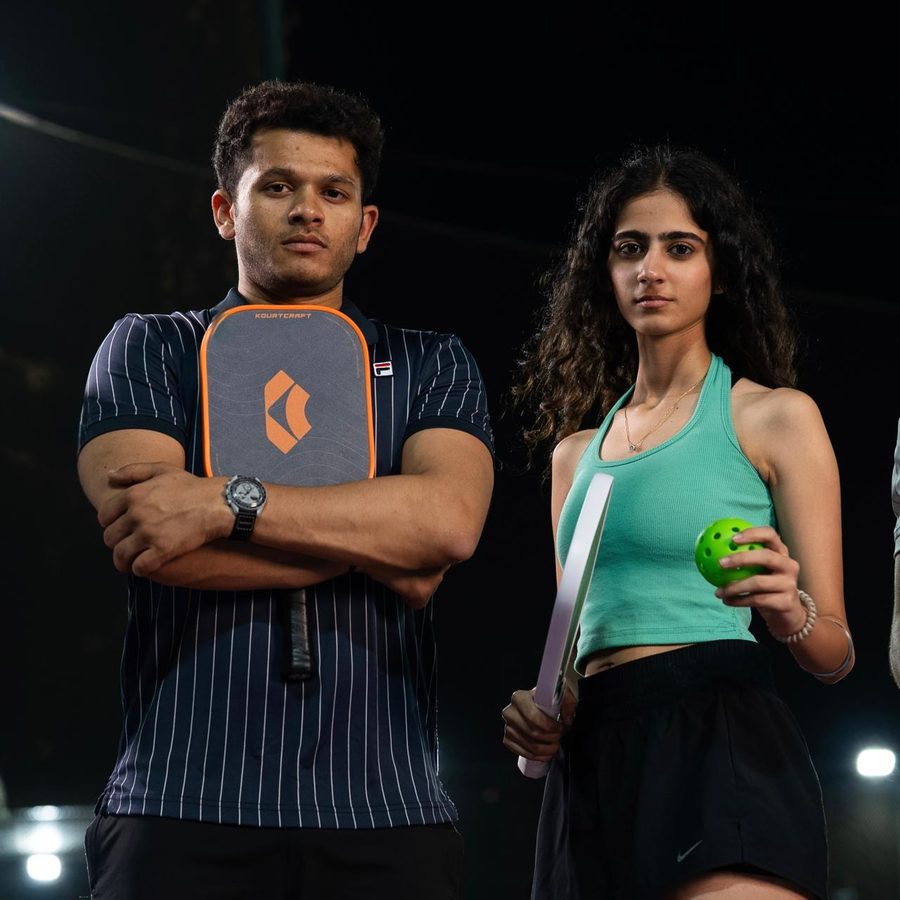 Two players with Kourtcraft pickleball paddles at Arena One at night